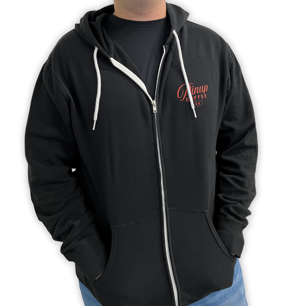 Male model showcasing a black Pinup Coffee Co zip-up hoodie