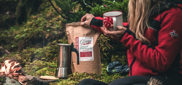 bag of coffee in the woods with a gift mug next to a fireplace