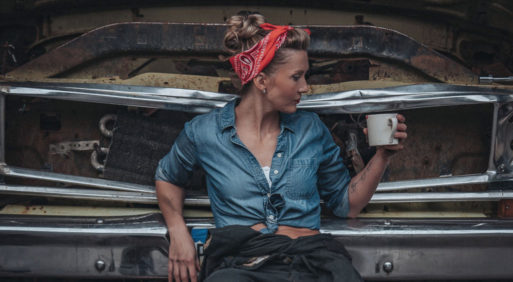 pin up girl in front of old car drinking coffee